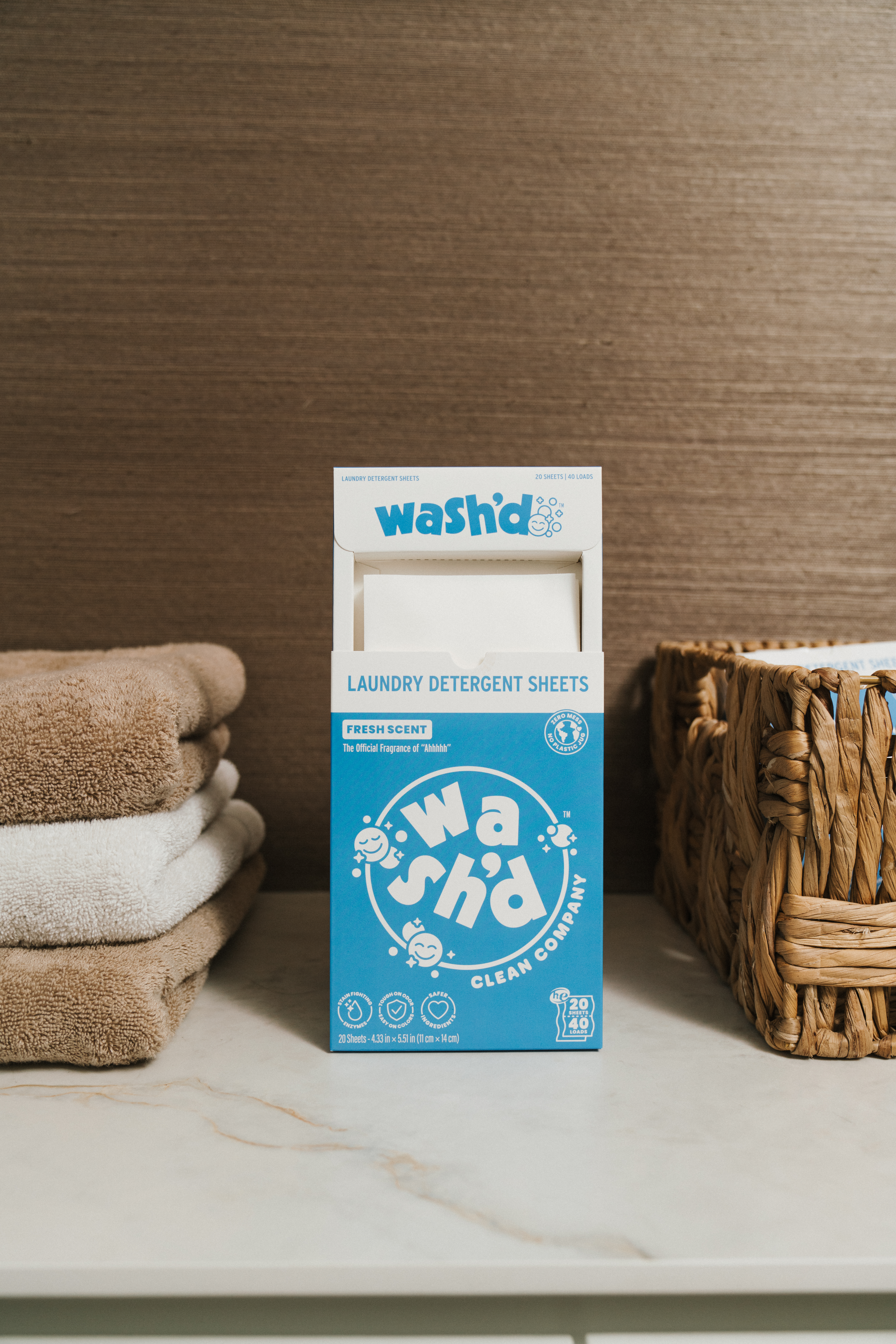 Flat-lay of a box of Wash'd detergent sheets on a white marble surface